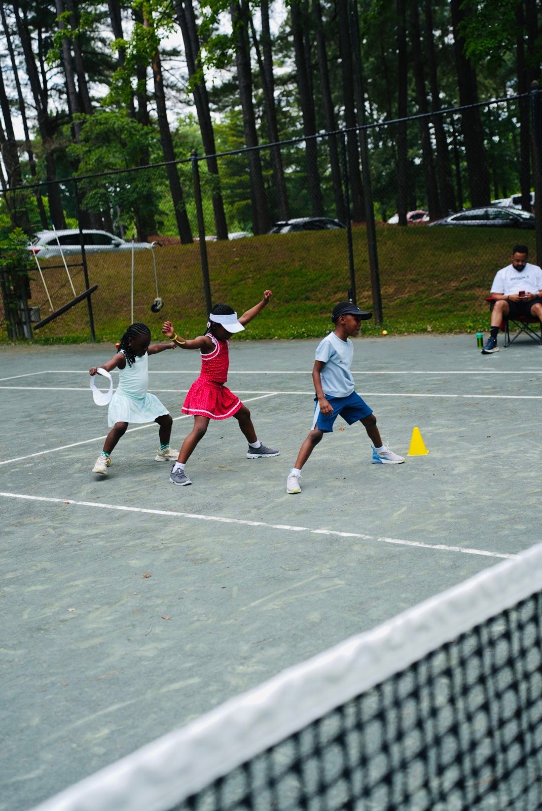 Three kids running a tennis drill at a Miles Ahead school tennis clinic